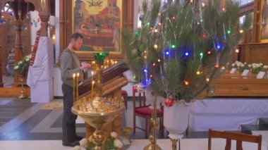 Altın seyir simgelerle Christian Katedrali, Saint görüntüleri ve ahşap sütunlar ve sakallı bir adam bazı simge önce dua bir Beuatiful dekorasyon