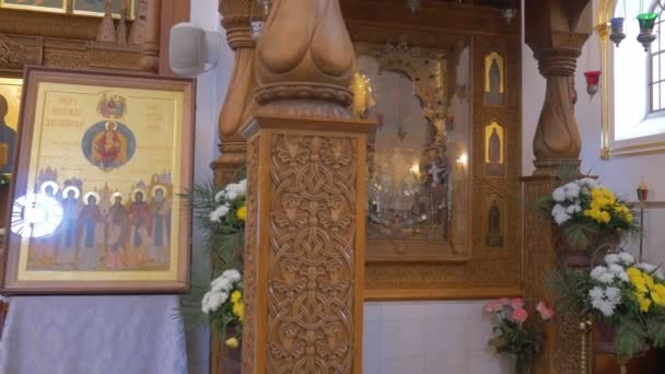 Eine antike Ikone der Heiligen Maria und einer vor ihr betenden Frau, im Inneren einer beeindruckenden orthodoxen christlichen Kirche in Kiev — Stockvideo