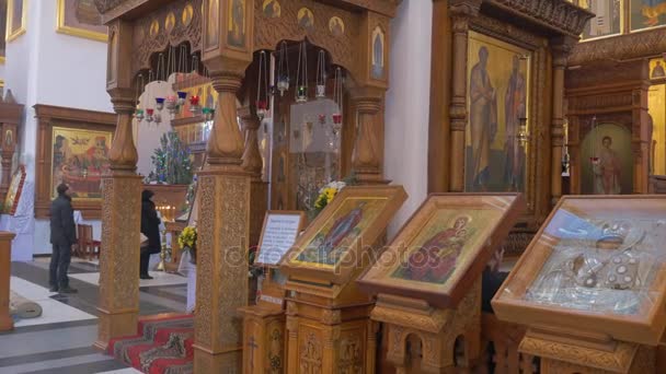 Un majestuoso icono de Santa María cubierto de vidrio, cubierto con un techo de madera tallada y dos columnas de pie cerca de una iglesia cristiana en Kiev — Vídeo de stock