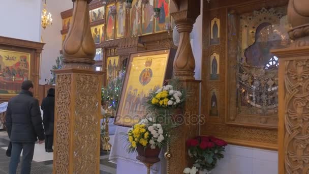 Oude gouden op zoek en mooie pictogrammen in een kerk, die behoren tot de orthodoxe christendom, en mensen Praing vóór hen — Stockvideo