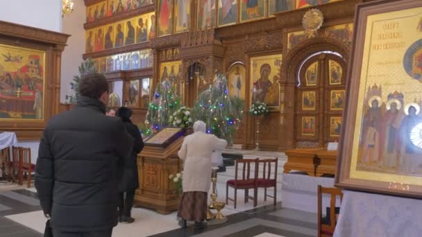 Een Man die overschrijding van zichzelf voor een oude iconostase, die ziet er prachtig en bedekt met Saint beelden, oude pictogrammen, gesneden houten decoratie in Kiev — Stockvideo