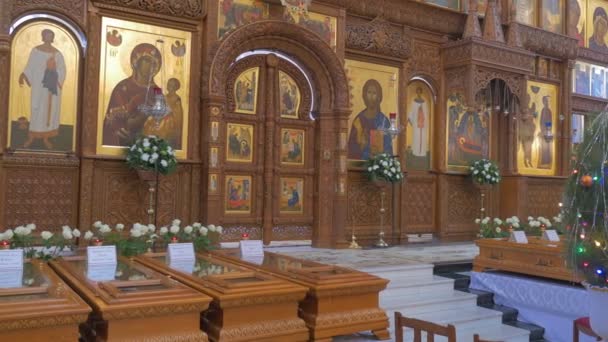 Majestätische Ikonostase im Inneren einer orthodoxen Kirche mit Heiligenbildern, goldenen Ikonen, Holzdekoration und Menschen, die davor stehen — Stockvideo