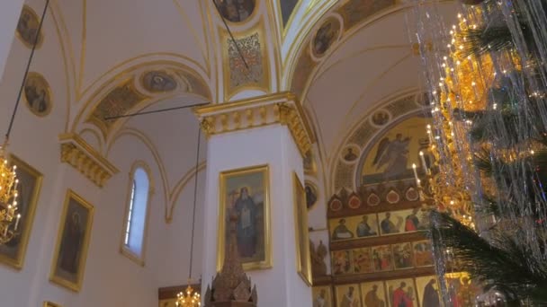 Un maestoso lampadario dall'aspetto dorato e soffitto a cupola alta con Saint I, matura su di esso, con un albero di abete diffuso e decorato nella Chiesa cristiana di Kiev — Video Stock