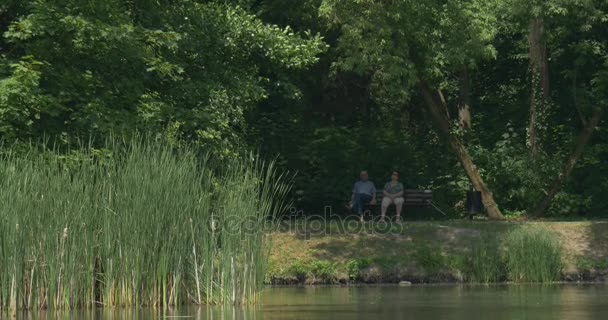 El hombre y su esposa descansan en la orilla del río — Vídeos de Stock
