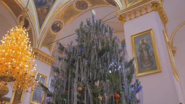 Un sapin impressionnant et un lustre splendide, qui décorent une vieille cathédrale orthodoxe avec un plafond à haute coupole et des images saintes dorées à Kiev — Video