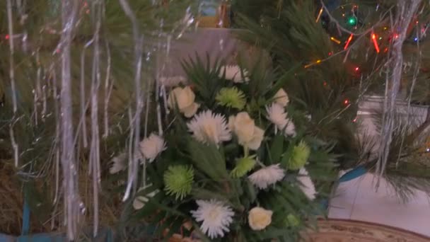 Un bouquet de fleurs et une icône de sainte Marie avec des anges sous un grand sapin décoré de jouets et de rayures de pluie argentées étincelantes dans une vieille église orthodoxe — Video