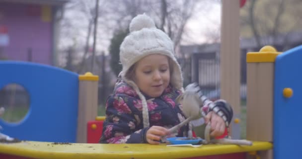 Εμπρόσθια όψη του το μικρό κορίτσι με το παιχνίδι στην παιδική χαρά — Αρχείο Βίντεο
