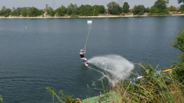 Een renner van een Wakeboard beweegt op een wateroppervlak met behulp van enkele lange touw en trok door sommige lucht-Object in de zomer — Stockvideo