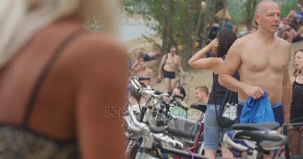 Молодые люди стоят рядом с кучей велосипедов, оглядываются, разговаривают и плавают на заднем плане летом в Польше — стоковое видео