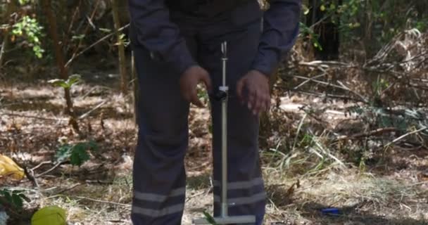 Человек поклоняется и поворачивает руку крепко, чтобы получить некоторые образцы почвы в диком лесу, чтобы проверить уровень загрязнения хранения нефти — стоковое видео