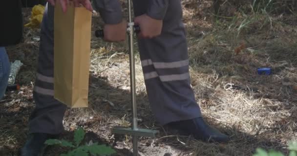 El hombre gira su abrazadera de mano para obtener muestras de suelo, tratando de explorar el nivel de contaminación química y biológica de un almacenamiento Oli — Vídeo de stock