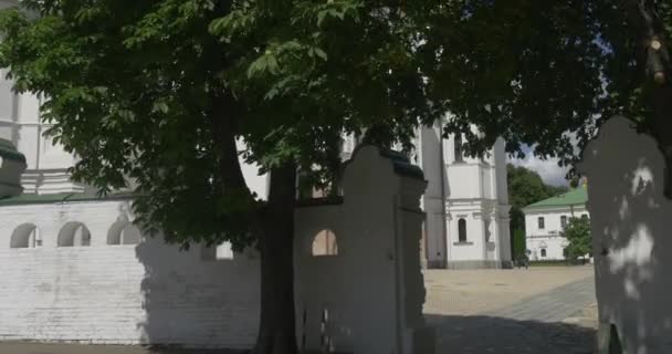 De witte stenen omheining van Uspensky Sobor en het indrukwekkende gebouw van deze kathedraal met gouden UI op zoek koepels en kruizen overdag — Stockvideo