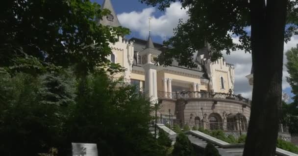 Чудесный левый трек Киевского академического театра кукол, проходящего сквозь ветки лиственных зеленых деревьев летом — стоковое видео