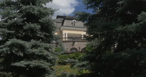 Eindrucksvoller blick auf das kiewer akademische puppentheater, das im sommer durch die zweige ausladender blautannen geschossen wird — Stockvideo