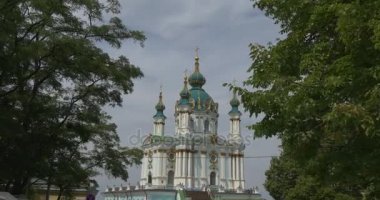 Saint Andrew's Kilisesi, Kiev, bulutlu bir hava yaprak döken yeşil ağaçların dalları ile görülen ana barok stili binada