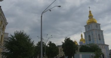 Eski kalıp ve bulutlu bir hava etkileyici kemer kaplı çan kulesi St.michael'ın altın kubbeli Manastırı, mavi duvar ile sol çekim izleme