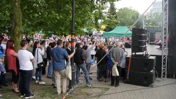 Centenas de espectadores estão olhando para jovens dançarinos que encenam um show em uma zona de parque com um monte de Greenary em um dia ensolarado na Polônia — Vídeo de Stock