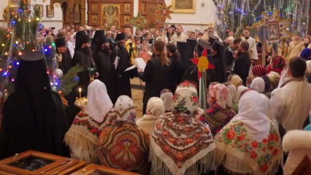 Vanligt folk träffas i en kristna kyrkan, dekorerad med en julgran, och sjunga sånger tillsammans med munkar och präster — Stockvideo