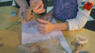 Clay Fish gülümseyen 6 yıl yaşlı kız ve bir profesyonel Bayan, kim oturup bir tablo ile bir çok kağıt, ahşap panoları ve özel kalemler ve sopa tarafından yapılan