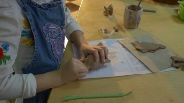 Clay Dolphin bir iyi görünümlü küçük sarışın kız kim kullanır tarafından tahta bir sopa şekil Her parça, kil, süre varlık bir çömlek atölyesinde çalışılır