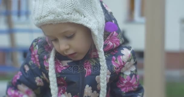 六年岁金发小女孩是在穿着彩色 Waiscoat，针织帽子与巴拉邦，粉红色的裤子，公园区玩在波兰的秋天 — 图库视频影像