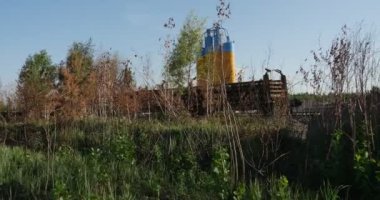 Petrol Depolama rezervuarlar gündüz yaz aylarında Ukrayna, bazı ahşap çit üzerinden yapışkanlık dışarı sarı ve mavi renklerde boyanmış