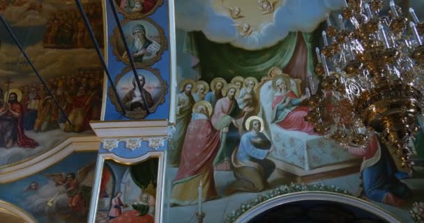 Lámpara dorada y un magnífico mural con Santa María acostada en su cama, entre numerosos santos sobre el fondo azul en una iglesia ortodoxa — Vídeos de Stock