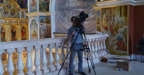Cámara Hombre está filmando las imágenes sagradas de la iglesia de la Asunción de la Santísima Virgen María desde el segundo piso — Vídeo de stock