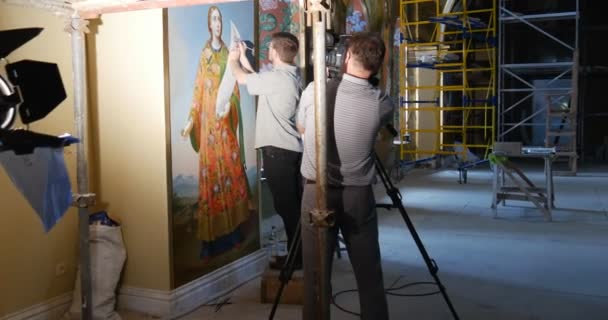 Kameramann dreht in der Werkstatt des Restaurators, der in der großen Marienkirche Mariä Himmelfahrt die Ikone der Heiligen Maria restauriert — Stockvideo