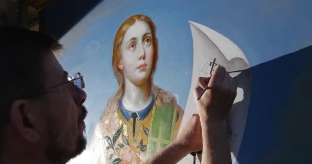 Restaurátor írja a régi szláv ABC néhány felirat néhány Szent kép szent szövegek tartva a karját, a Szűz Mária Mennybevétele templom — Stock videók