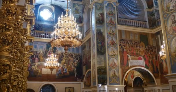 Lampadari impressionanti, colonne dall'aspetto dorato, icone e grandi murales all'interno della Chiesa dell'Assunzione della Beata Vergine Maria a Kiev — Video Stock