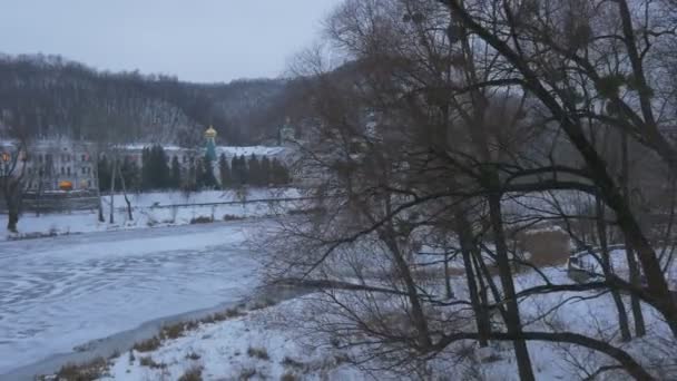 Klášter od zamrzlé řeky Sviatohirsk lávra zamračený mrazivý den Sněžná krajina z horského terénu exteriér kostela zimní pohled výletní turizmus — Stock video