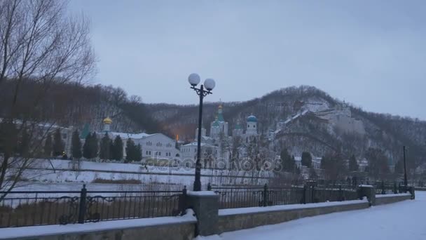 Turisti che guardano la vista invernale delle sagome della chiesa in nuvoloso ghiacciato sera passeggiata lungo Seversky Donets Riever paesaggio innevato Esterno del monastero — Video Stock
