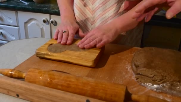 Женщина объясняет, как сделать это с помощью деревянной плесени семья готовит за столом традиционный семейный ужин — стоковое видео