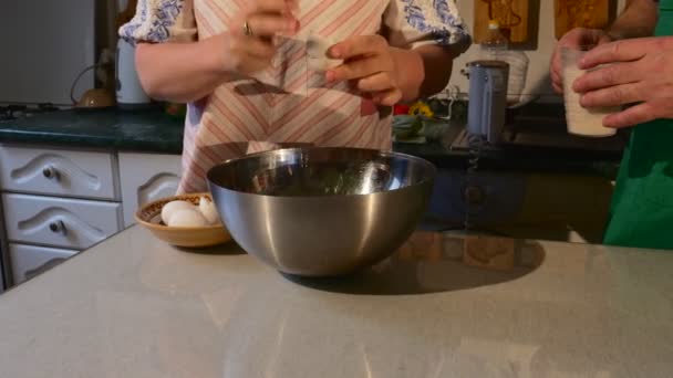 Kvinnan är att bryta ägg och sätta den i en skål kommer att göra en deg hemmagjord bakning personer är matlagning hemma mormor och morfar väntar för besökare — Stockvideo