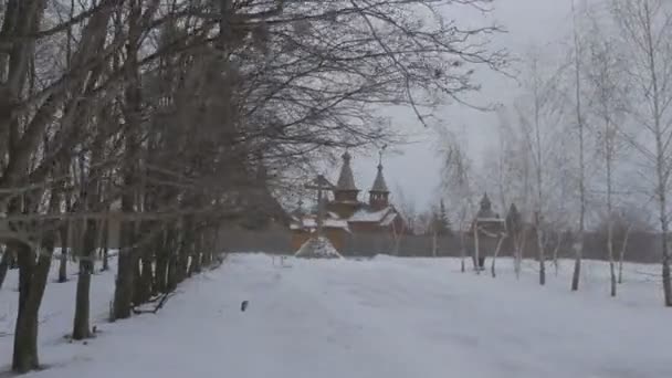 Église orthodoxe en bois de tous les saints Sviatogorskaya Lavra clôturé avec clôture en rondins élevée Vue à travers le parc d'arbres nus en soirée Crépuscule d'hiver Voyager — Video