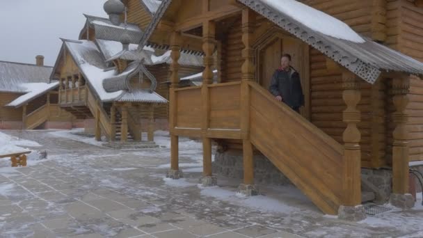 冬期積雪日歴史的な観光地の Sviatogorskaya Lavra 諸聖人の彫刻が施された木製の階段伝統的なロシア Terem 寸劇で階下を歩く男 — ストック動画