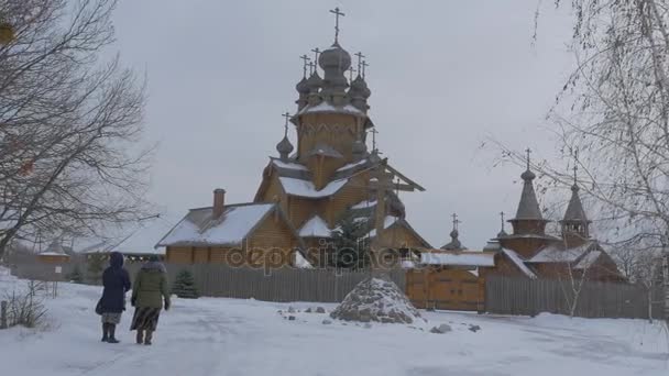 Deux femmes regardent le célèbre monastère en bois de l'église orthodoxe appelé Sketch Vsekh Svyatykh à Sviatogorskaya Lavra Les fidèles visitent l'église en hiver — Video