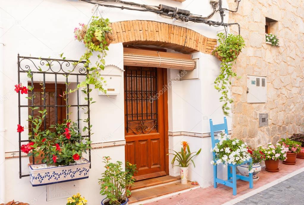 Chair and flower pots decorate home exterior in narrow Spanish t