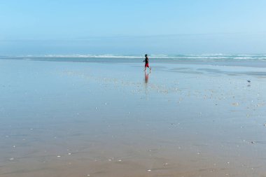 Boyunca t tarafından geniş düz kum üzerinde yürüyen adam küçük uzak rakam