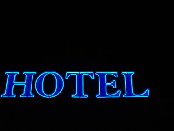 Helder blauwe hotel lichtreclame tegen zwarte achtergrond — Stockfoto