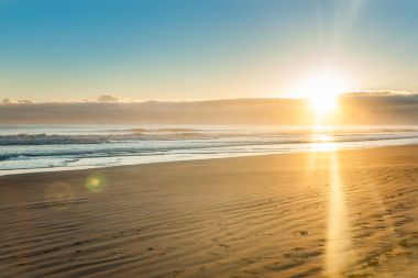 Ohope Whakatane, geniş düz kumlu plaj üzerinde gündoğumu
