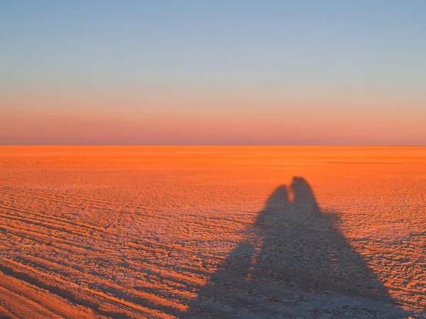 Shimmering horizon and long shadows as sun sets across Makgadikg