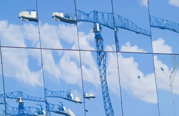 Imagens distorcidas de guindastes de construção refletidas em grande porte — Fotografia de Stock