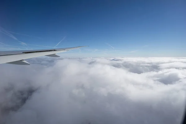 Aile d'avion au-dessus des nuages sous un ciel bleu clair . — Photo