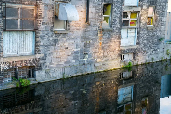 Old brick buildingsin process of redevelopment into city apartments reflected in canal below. — Stock Photo, Image