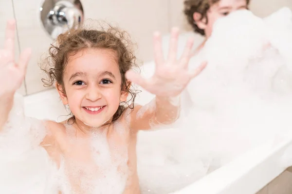 Счастливый ребенок в ванной, покрытый пузырьками — стоковое фото