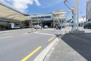 Auckland, Yeni Zelanda - 23 Kasım 2017 insanlar genç çift entranance doğru yol Uluslararası Havaalanı terminaline geçiş takım elbise durumlarda çekerek dahil olmak üzere.