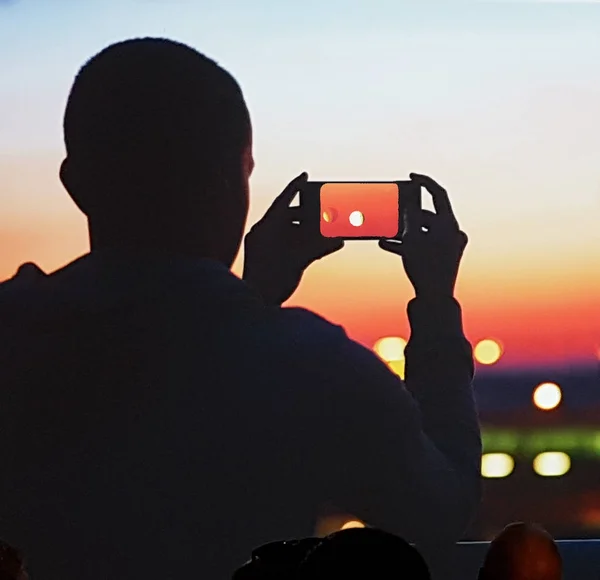 Зернистый мобильный телефон изображение силуэта человека, фотографирующего солнце — стоковое фото