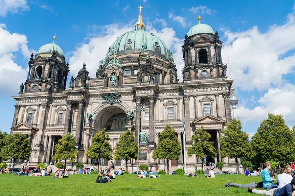 La gente se relaja bajo el sol en el césped fuera de la Catedral de Berlín — Foto de Stock